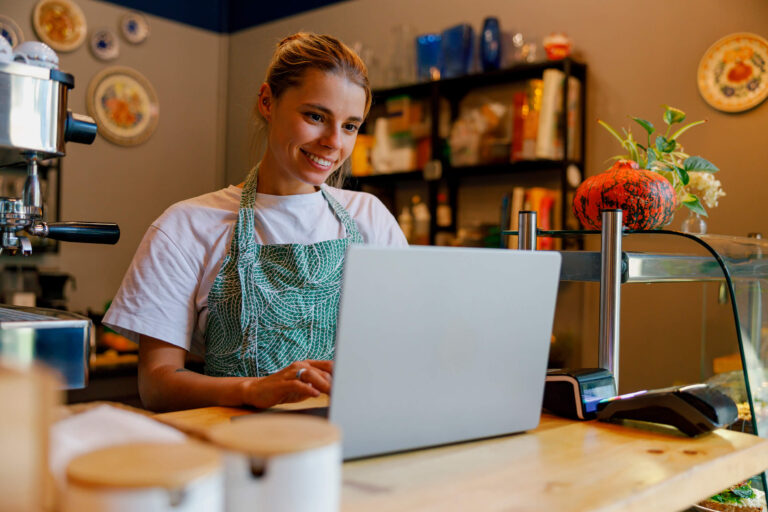 Dona emprenedora gestionant xarxes socials des d’un portàtil en un cafè.